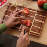 Load image into Gallery viewer, A tomato being cut on a brick pattern wooden cutting board made from Walnut and Birch Wood. 
