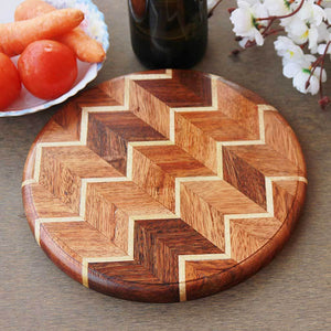 A chevron pattern cheese board or cutting board made from walnut wood and birch wood.