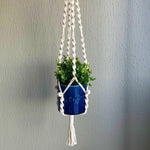 Load image into Gallery viewer, White macrame plant hanger with a succulent houseplant in a blue planter hanging from the ceiling
