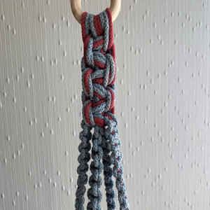 A close up shot of macrame knots on a blue and maroon two-toned macrame plant hanger