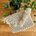 Load image into Gallery viewer, A white macrame envelope clutch bag on a table with an ivy plant
