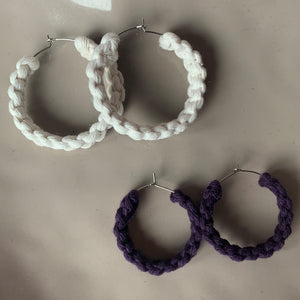 Two pairs of handmade macrame earrings in white and purple in small and medium sizes.