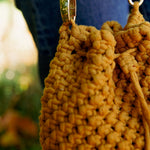 Load image into Gallery viewer, Macrame knot detailing on a mustard yellow macrame bucket bag with draw string closure
