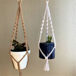 Load image into Gallery viewer, A set of two macrame plant hangers, a brown and a white macrame plant hanger with plants in a white and a blue  planter
