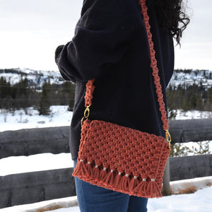 A woman carrying a brick coloured woven shoulder bag with a detachable strap