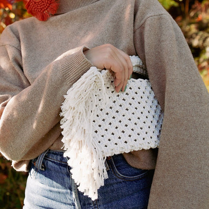 A girl holding a white bohemian macrame bag with fringe detailing