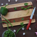 Load image into Gallery viewer, A striped walnut wood and birch wood cutting board with a bell pepper and coriander leaves on it
