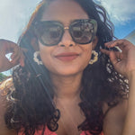 Load image into Gallery viewer, A brown woman wearing a pair of white macrame earrings in a hoop style.
